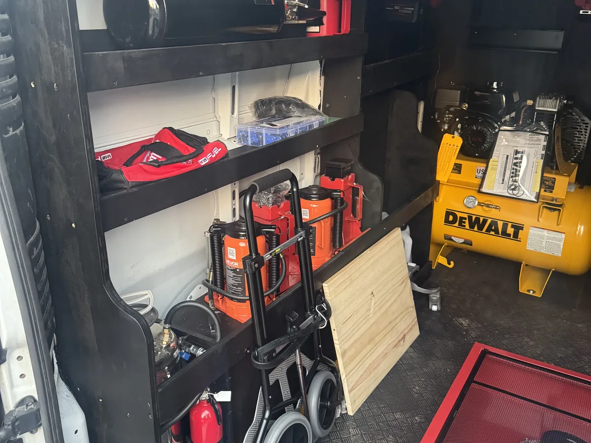 Shelving inside a service van stocked with power tools, jacks and an air compressor